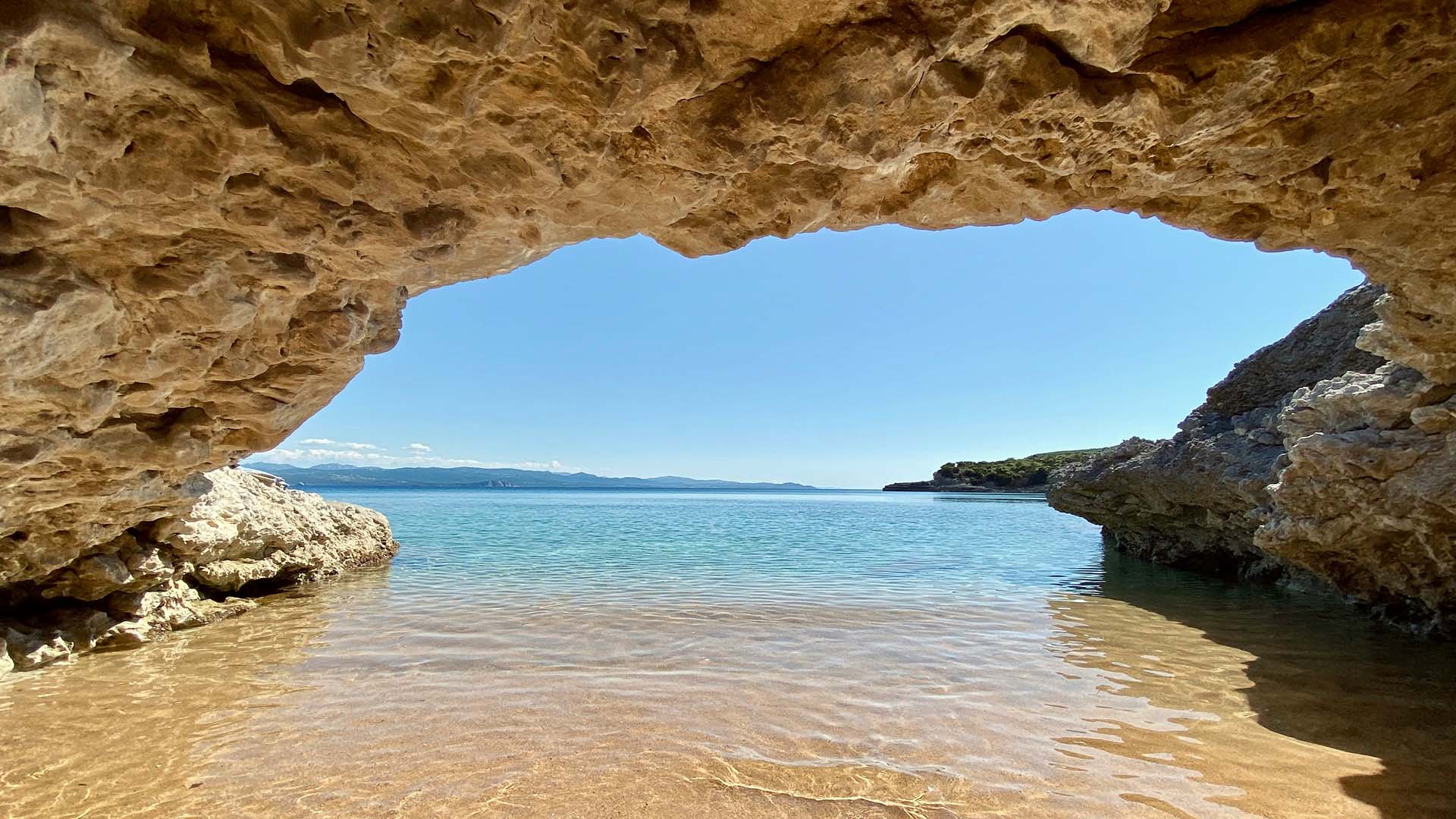 vista di una spiaggia della Sardegna da una grotta