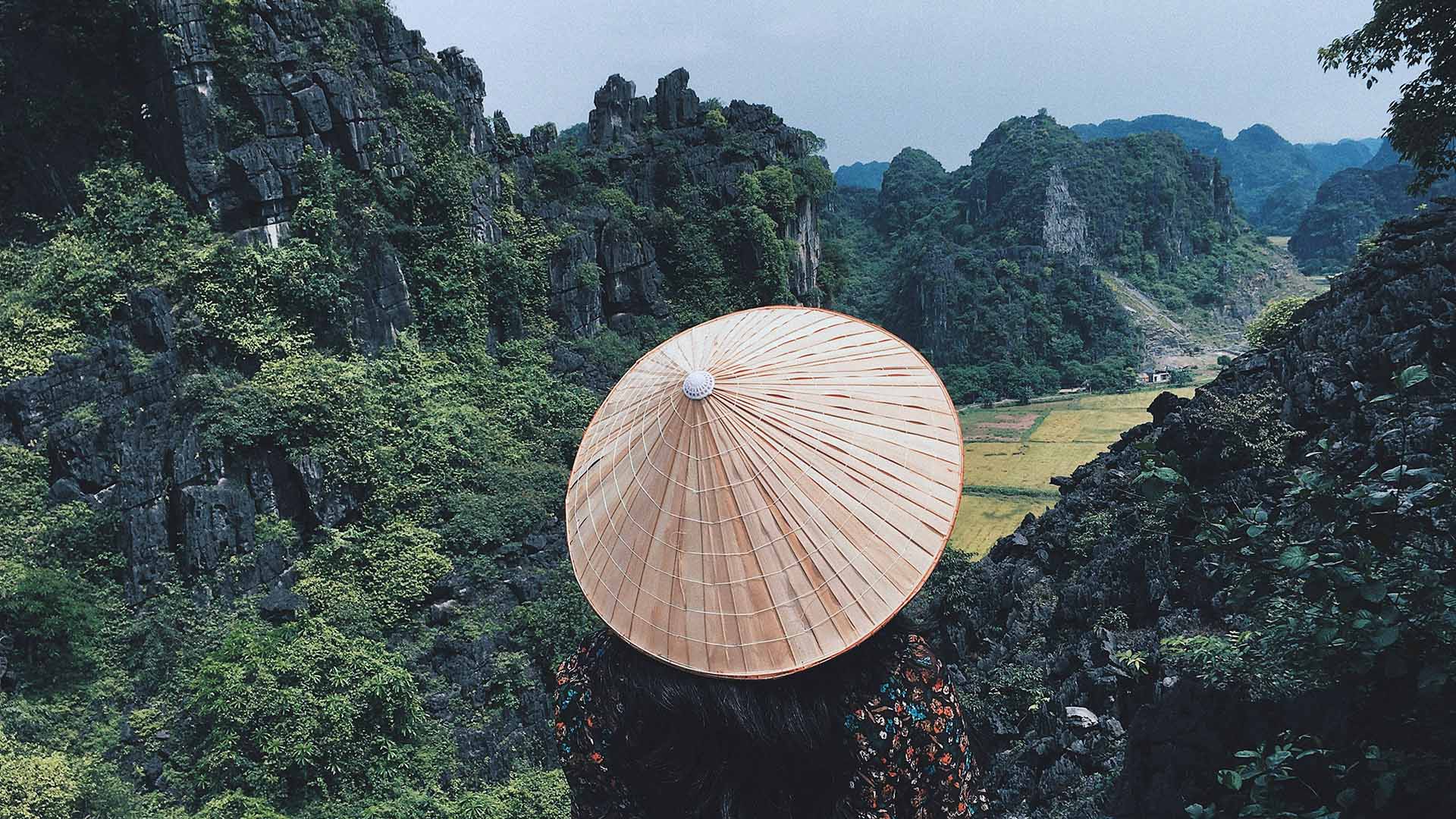 donna con tipico cappello vietnamita in bamboo che guarda il panorama